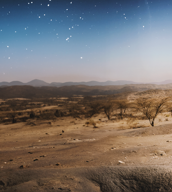 Image of a pastoral farmer walking amongst a dry and arid landscape.