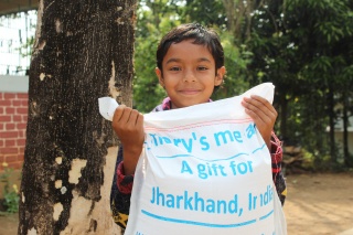 A boy in India holds a delivery of food from Mary's Meals