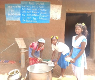 Arushi, a school pupil in India being served Mary's Meals by a volunteer at her school.