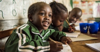 A child eagerly takes notes in class