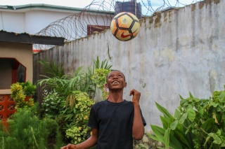 A boy keeps a football up in the air 