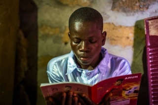 A young boy reads at a book at school.