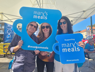 Mary's Meals volunteers and supporters holding signs. 